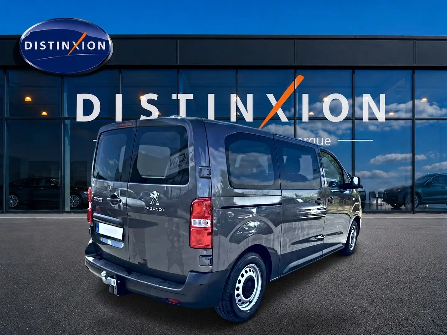 Vue 3/4 arrière droite du Peugeot Expert Fourgon gris 2024 avec porte latérale coulissante et attelage visible.