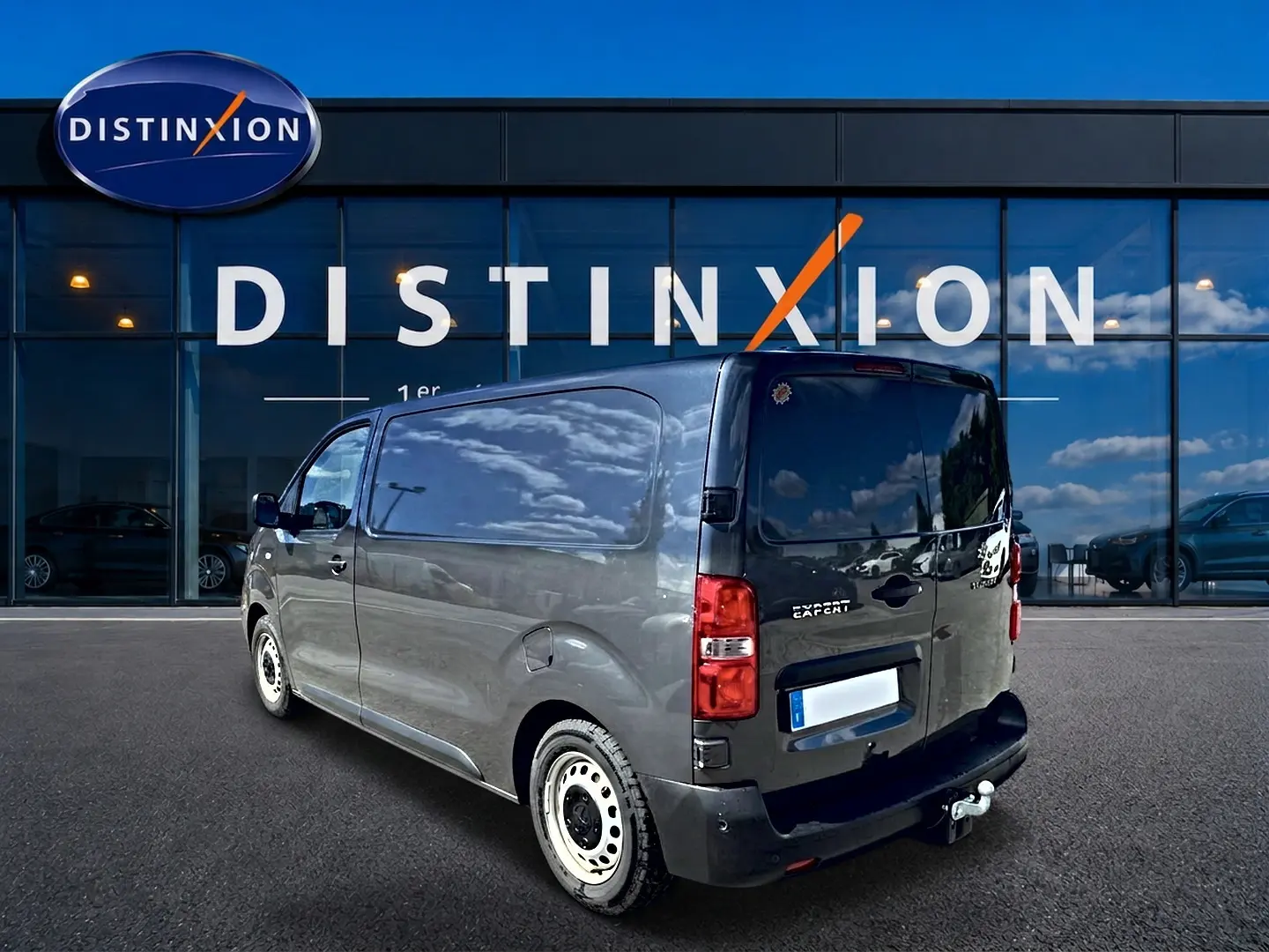 Vue 3/4 arrière droite du Peugeot Expert Fourgon gris 2024 avec porte latérale coulissante et attelage visible.