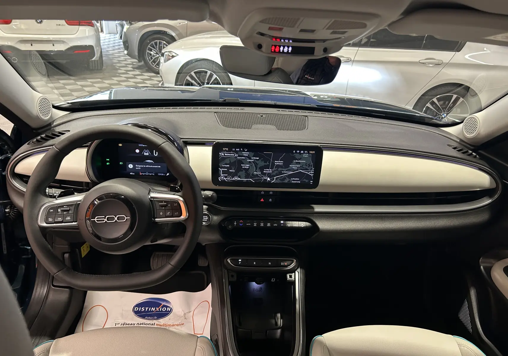 Intérieur du Fiat 600 Hybrid 2024 en bleu, vue de face sur le tableau de bord avec écran tactile et volant multifonction.