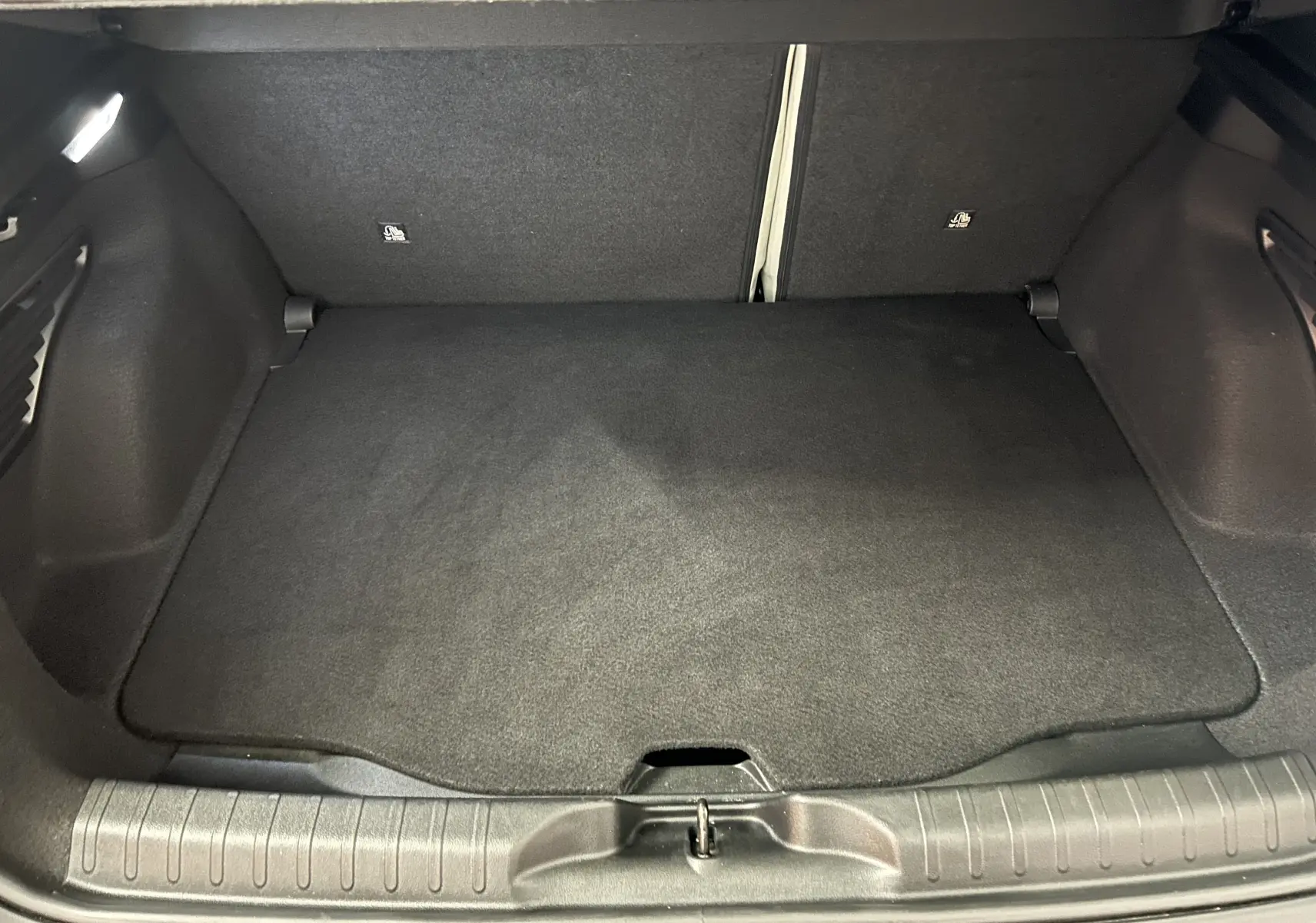 Coffre spacieux et propre de la FIAT 600 Hybrid 100 La Prima, vue arrière avec tapis noir et hayon ouvert.