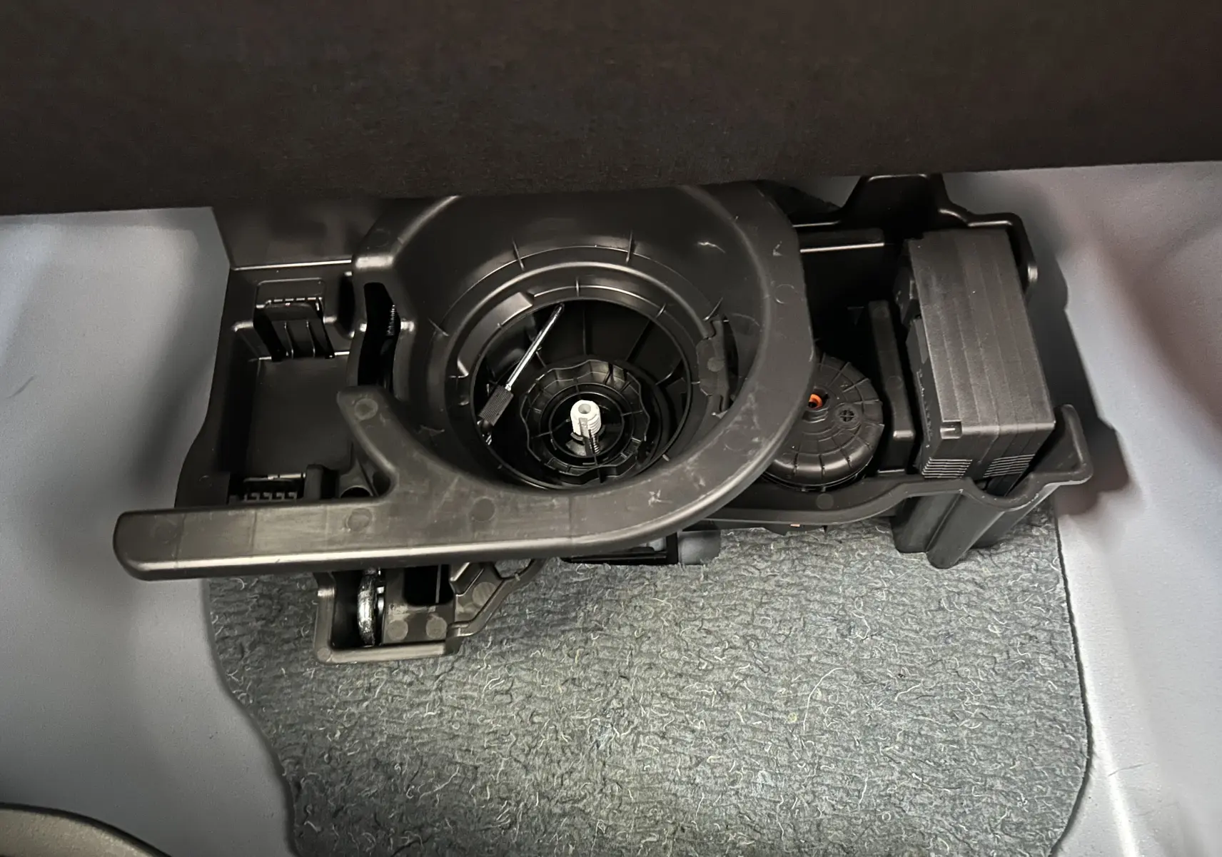 Gros plan sur le compartiment sous le plancher du coffre du FIAT 600 Hybrid 2024 montrant un outil de roue de secours.
