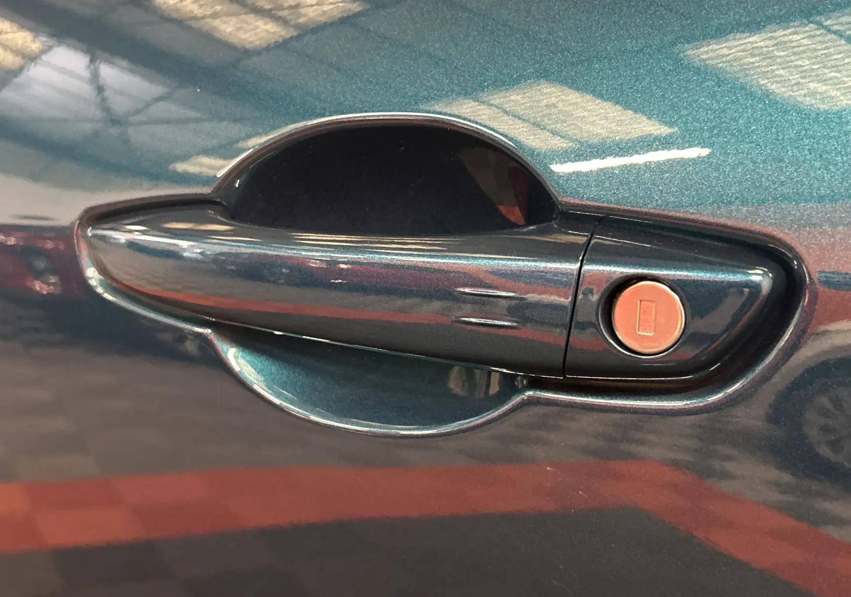 Poignée de porte bleu métallisé de la FIAT 600 Hybrid 2024 avec serrure intégrée, vue en gros plan côté droit.