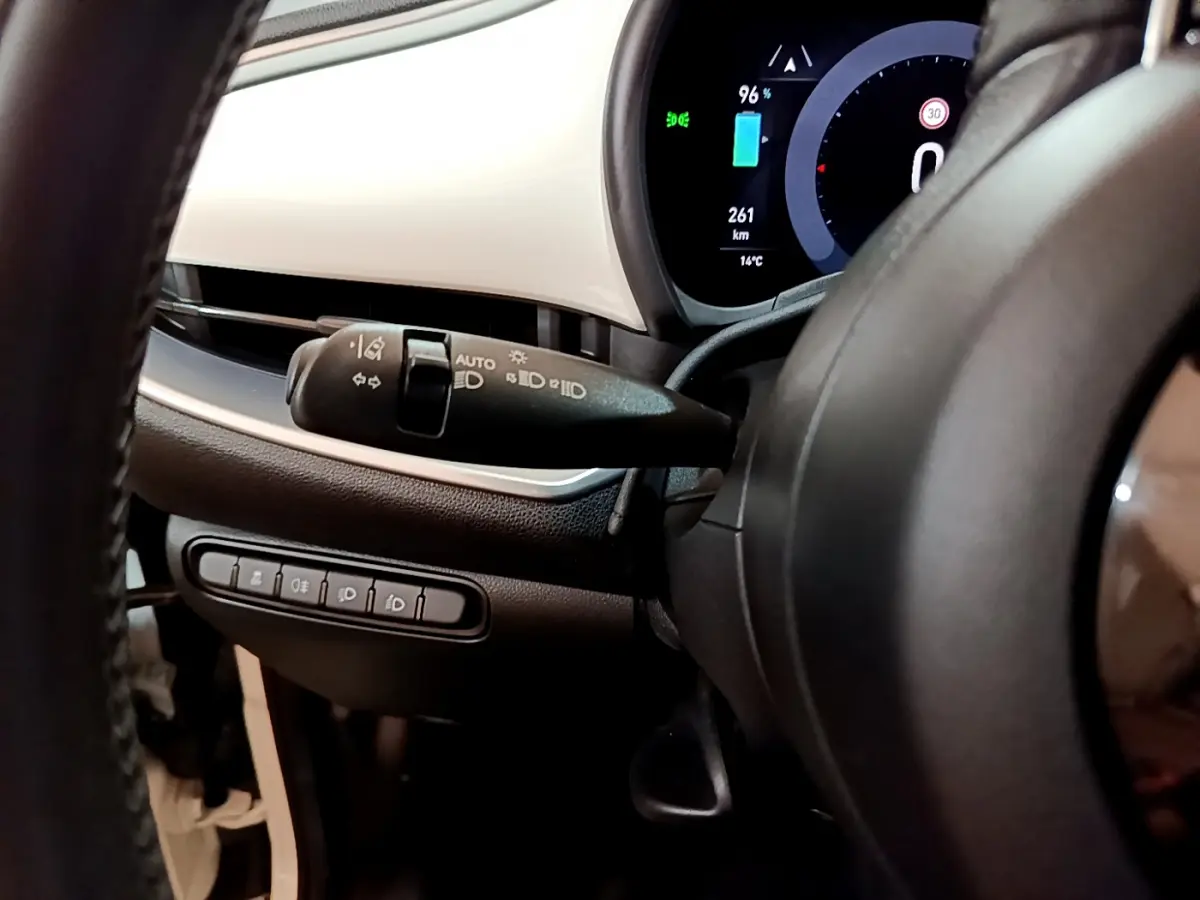 Gros plan sur le combiné d'instruments numérique et la commande des phares à gauche du volant d'une Fiat 500 blanche électrique 2022.