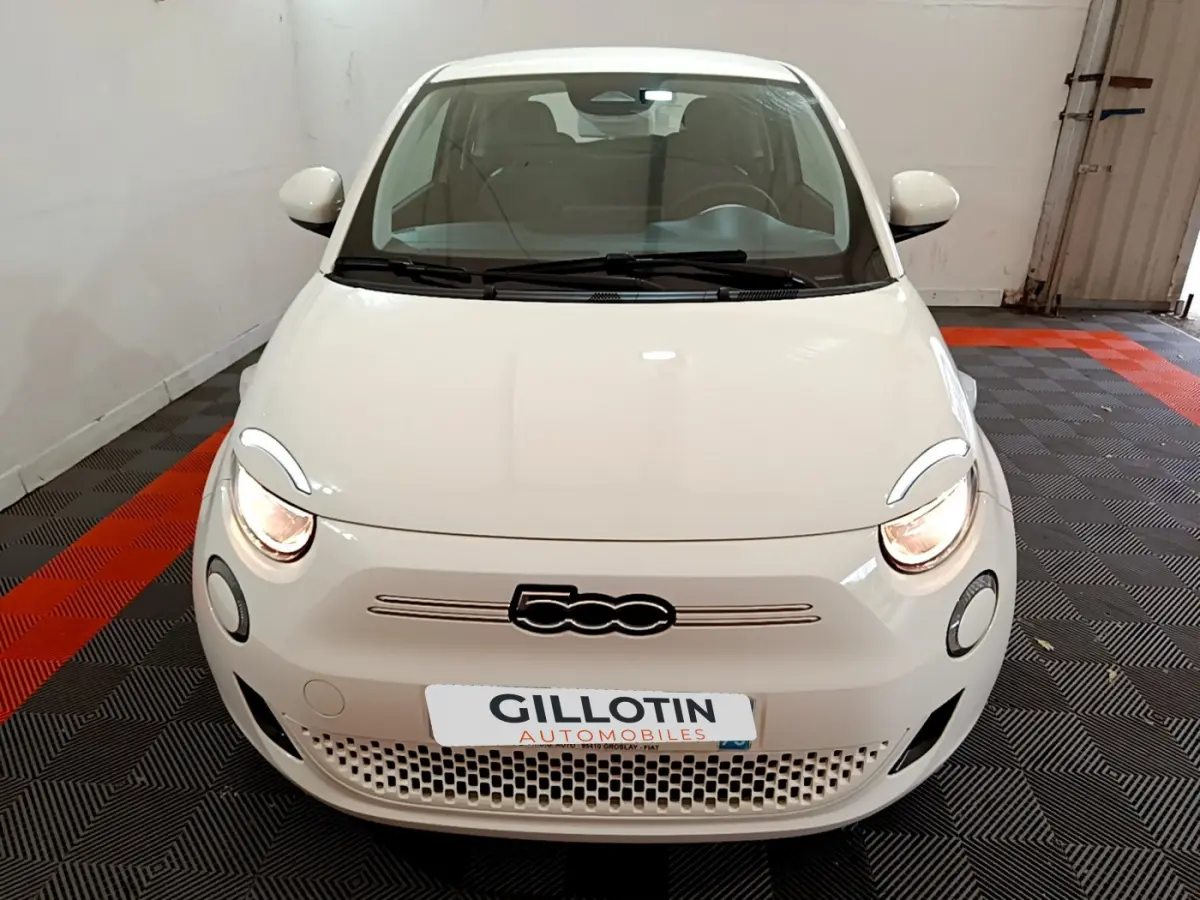 Vue avant d'une Fiat 500 électrique blanche 42kWh Icône avec phares allumés dans un garage.