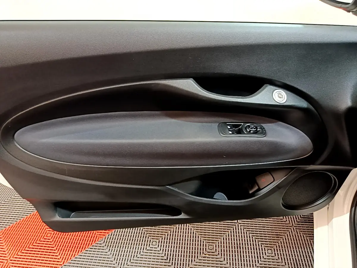 Gros plan sur la porte intérieure côté gauche d'une FIAT 500 blanche 42kWh Icône avec commandes de vitres et haut-parleur intégré.