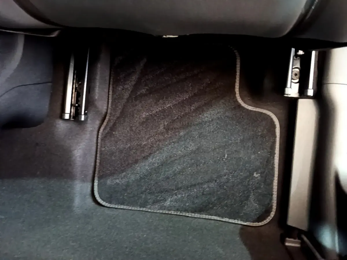 Vue rapprochée du pédalier côté conducteur de la Fiat 500 électrique blanche, avec tapis de sol noir.