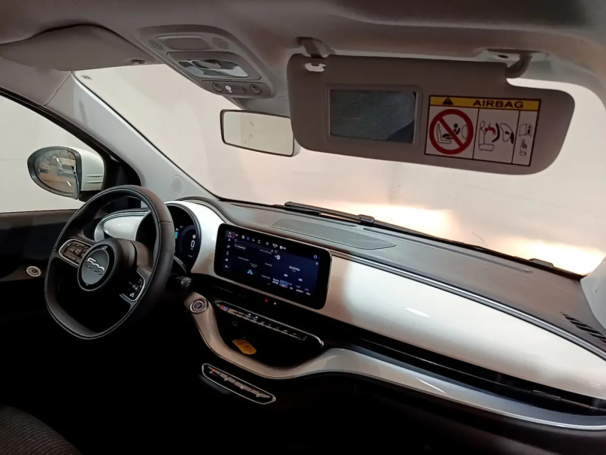 Intérieur avant gauche de la Fiat 500 électrique blanche 2022, tableau de bord moderne avec écran tactile central.