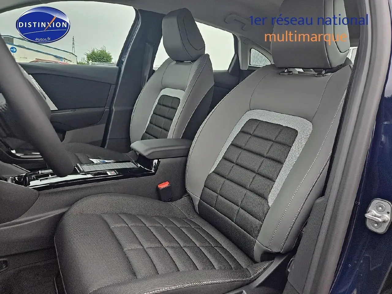 Vue intérieure côté conducteur de la Citroën C4 1.2 hybride 145 plus bleu eclipse, sièges tissu noir et gris avec accoudoir central.