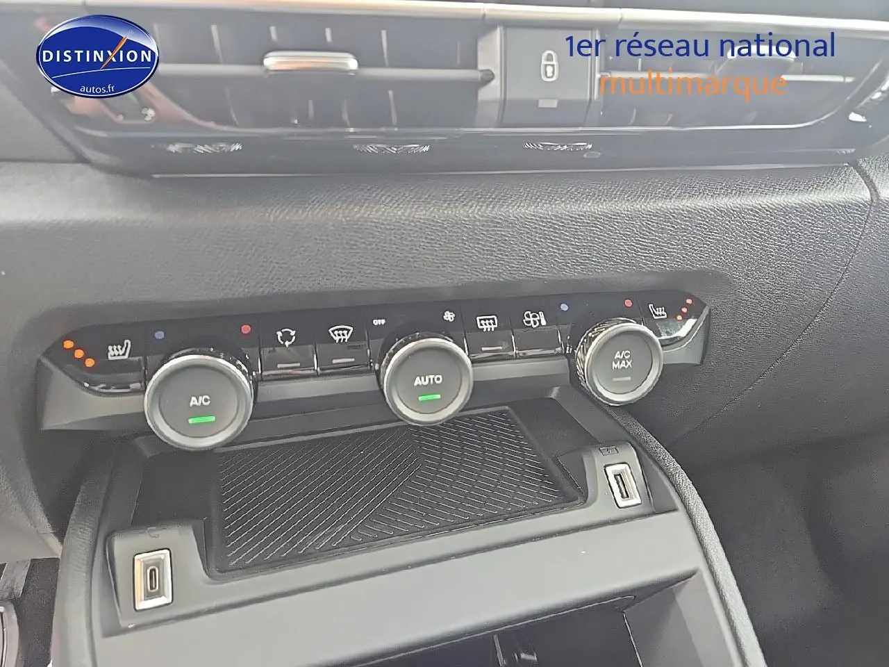 Vue rapprochée de la console centrale noire de la Citroën C4 Bleu Eclipse 2025 avec commandes climatisation et prises USB visibles.