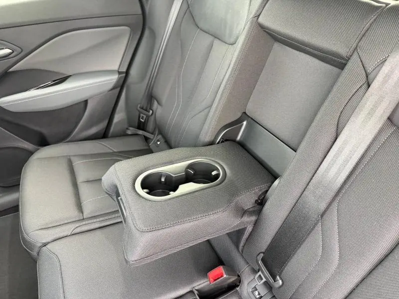 Vue intérieure du siège arrière droit de l’Audi Q3 2026 noir Mythique, avec accoudoir central rabattable et porte-gobelets intégrés.