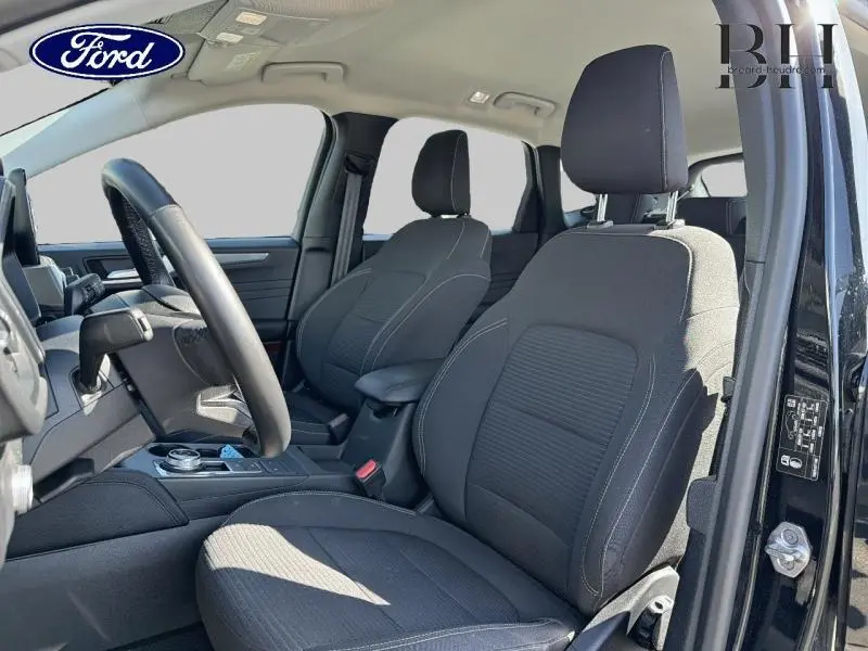 Vue intérieure côté gauche du Ford Kuga 2023 noir Agate, montrant les sièges avant sport et le volant cuir multifonction.