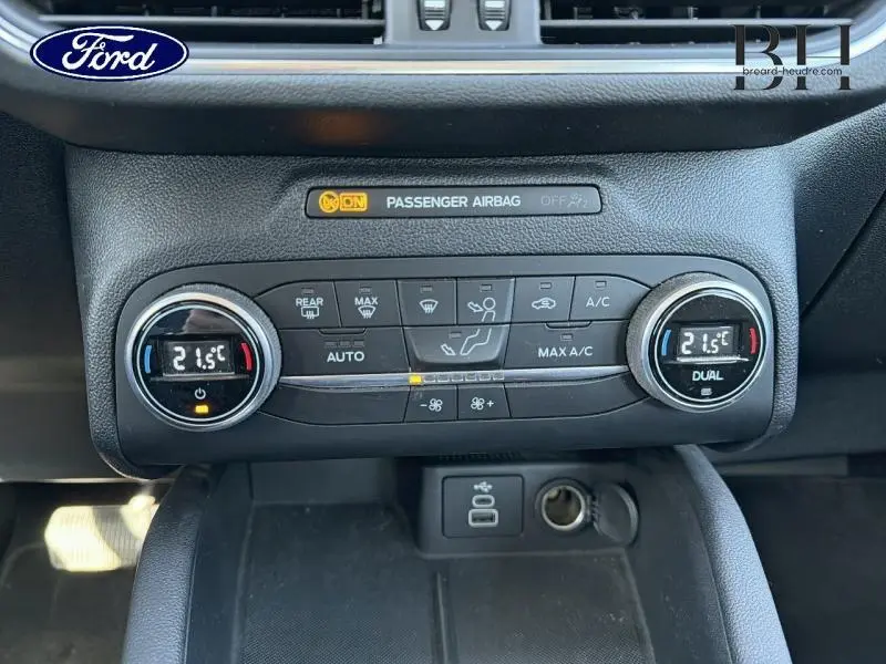 Gros plan sur la console centrale noire du Ford Kuga 2023, affichant la climatisation digitale à 21,5°C en mode dual.