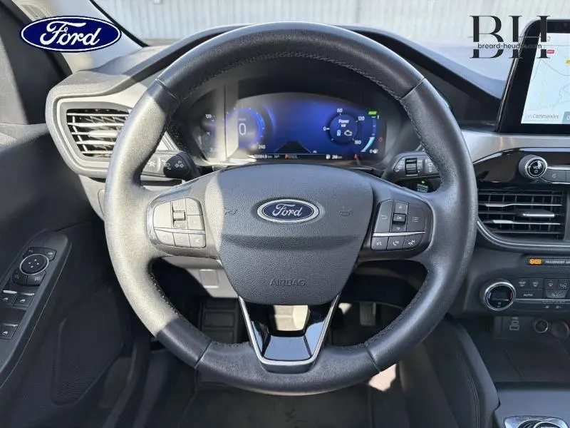 Vue centrée sur le volant cuir multifonction d'une Ford Kuga 2023 avec tableau de bord numérique et écran tactile.