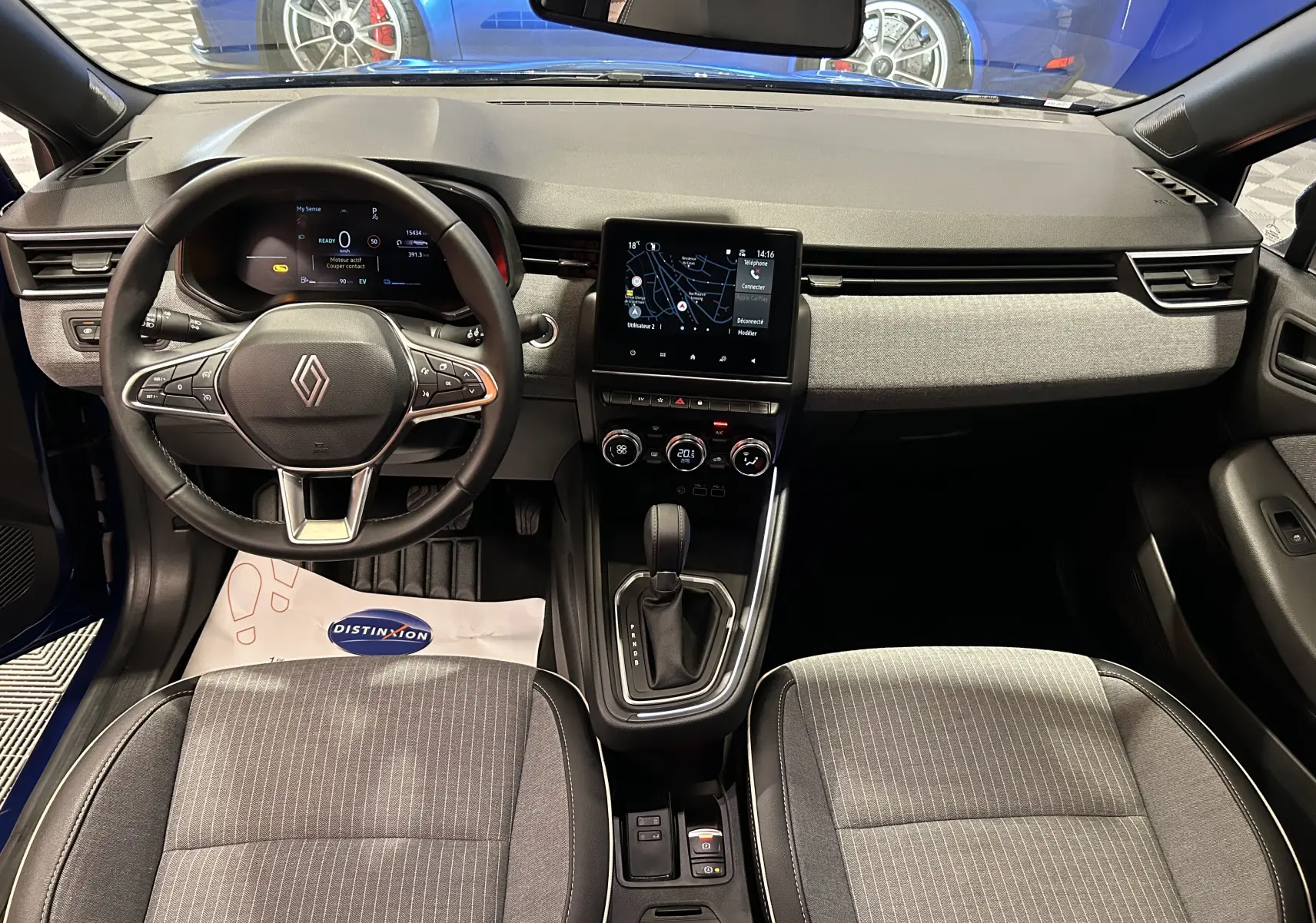 Vue intérieure avant de la Renault Clio V E-Tech hybride, tableau de bord moderne avec écran tactile et volant multifonction noir.