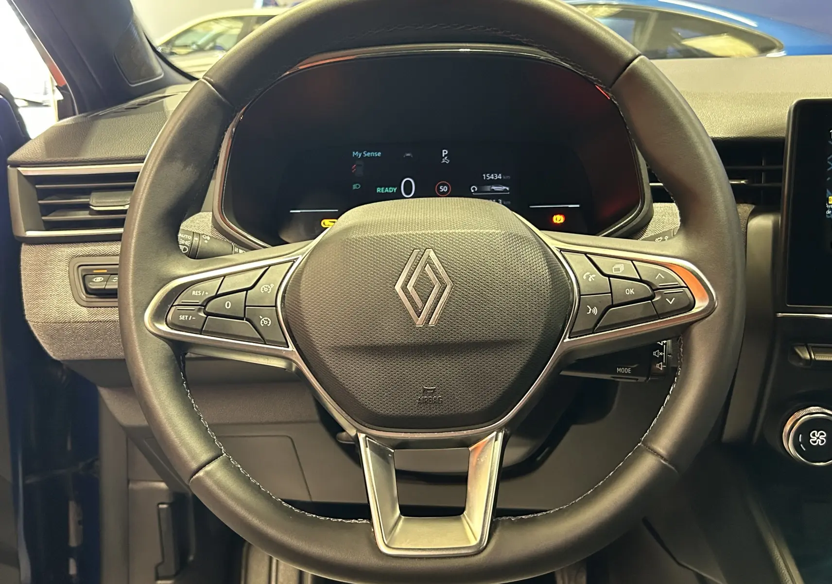 Vue rapprochée du volant noir de la Renault Clio V E-Tech avec commandes intégrées et tableau de bord digital.