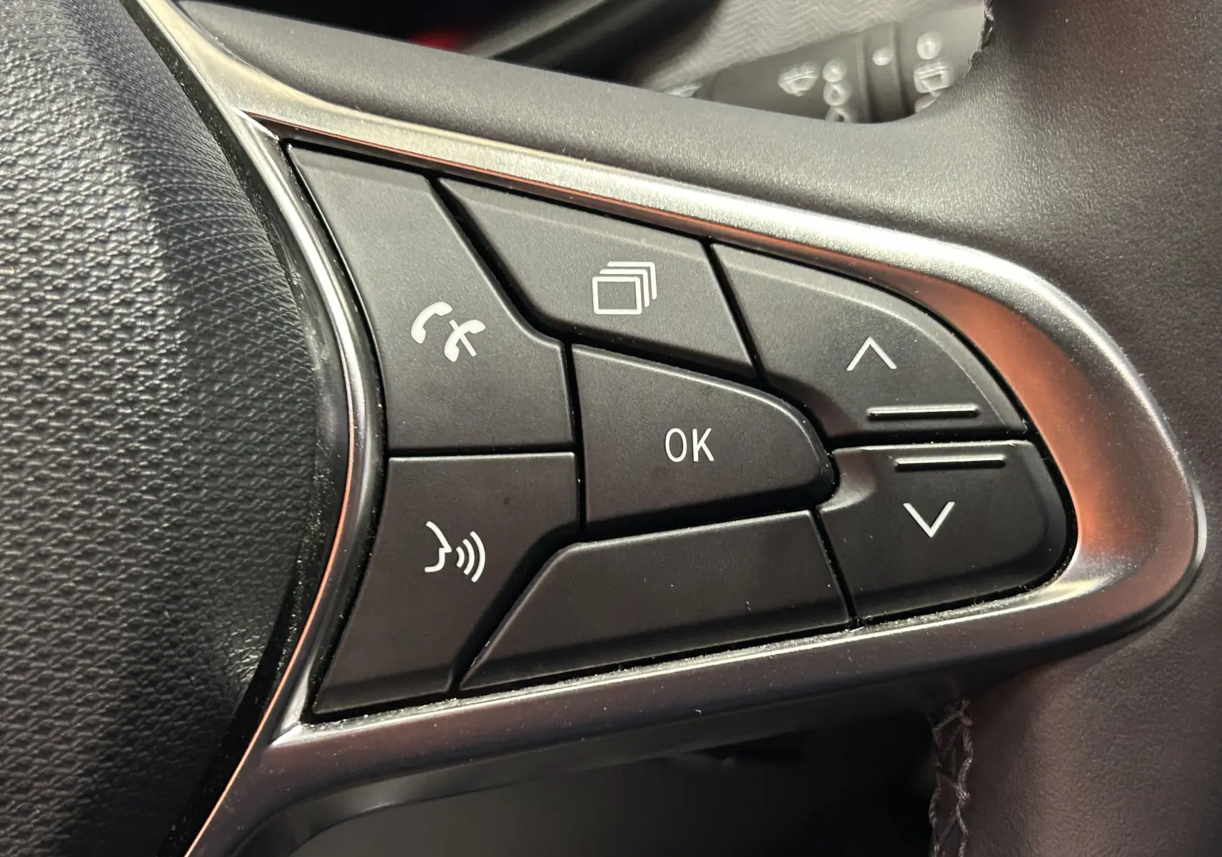 Gros plan sur les commandes multifonctions noires du volant de la Renault Clio V, finition intérieure gris noir.