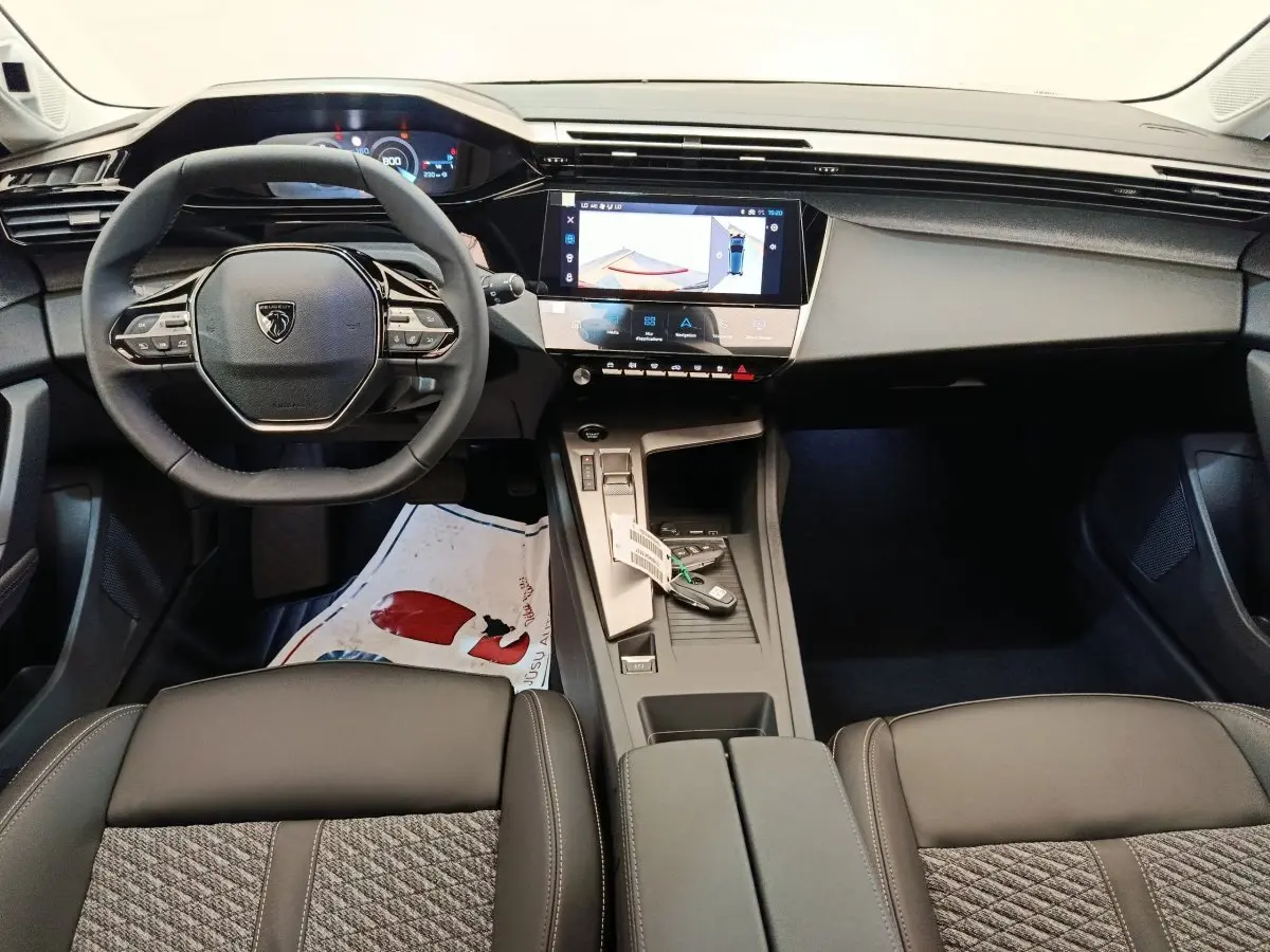 Vue intérieure avant de la Peugeot 308 2026, volant cuir multifonctions, écran tactile central et console gris foncé.