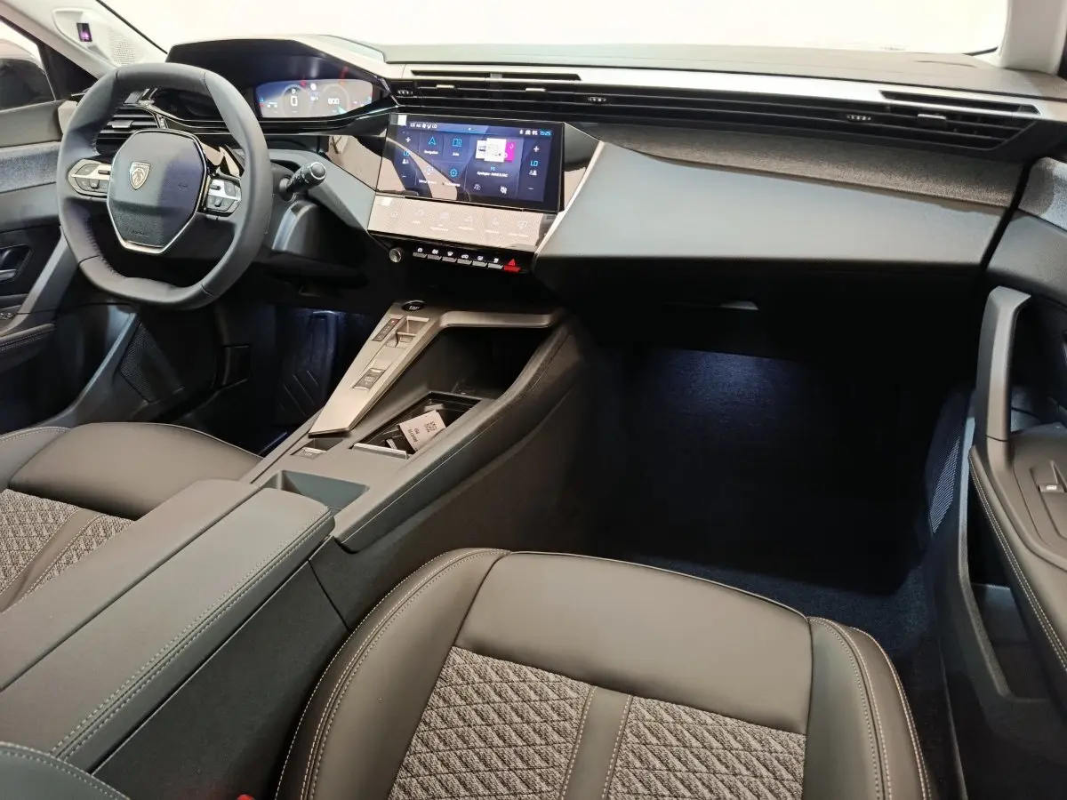 Intérieur avant de la Peugeot 308 2026, vue côté conducteur, volant cuir multifonctions et écran tactile central.