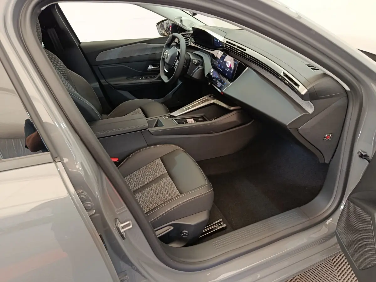 Vue intérieure côté conducteur de la Peugeot 308 gris foncé 2026, avec volant cuir multifonctions et écran tactile central.