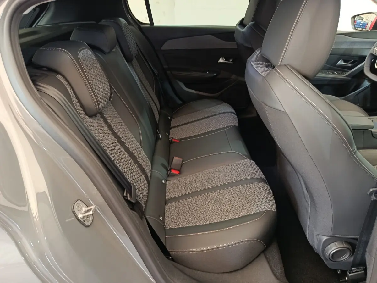 Vue intérieure côté gauche montrant la banquette arrière bi-matière grise et noire du Peugeot 308 BlueHDi 130 Allure 2026.