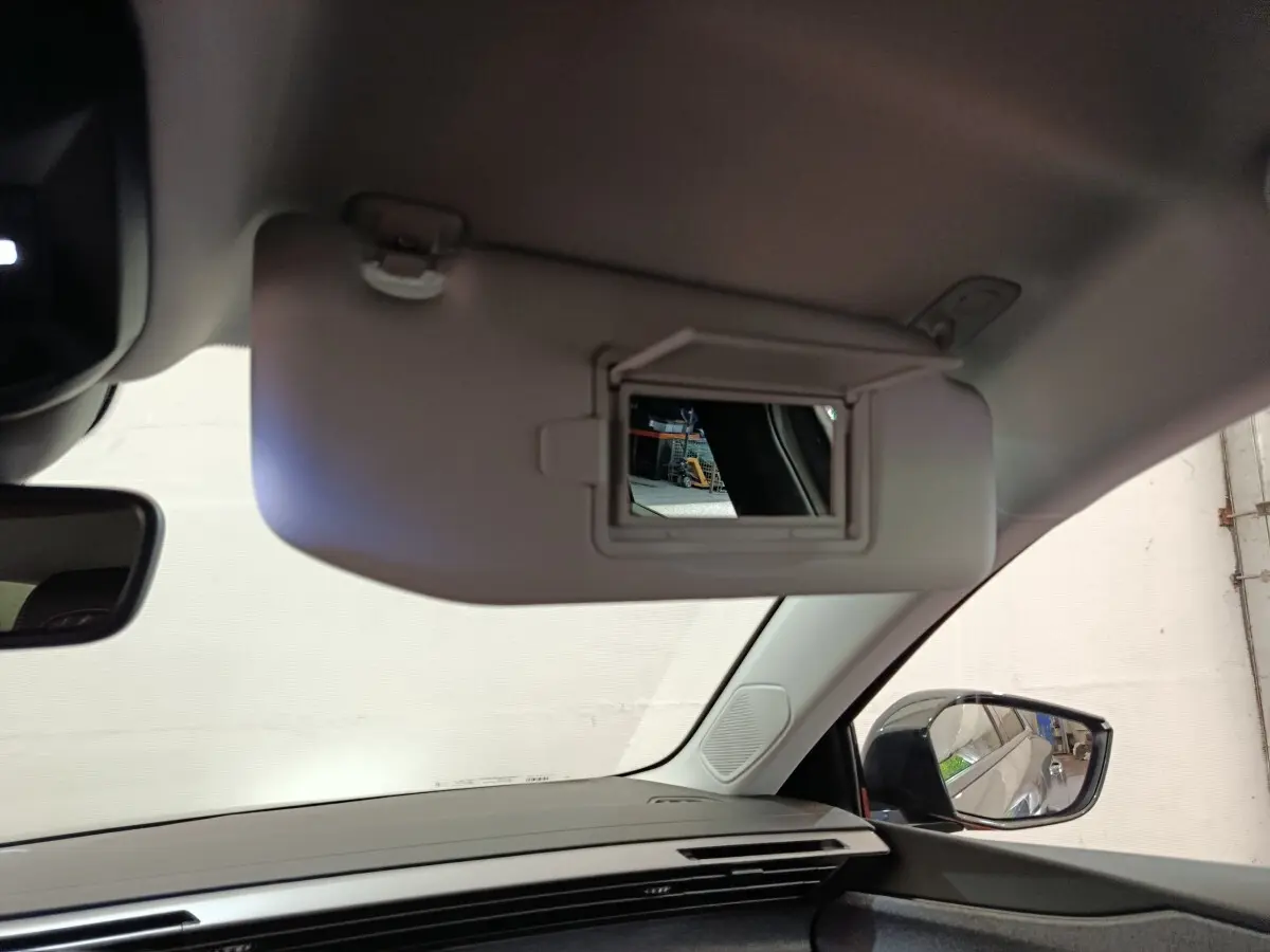 Intérieur du Peugeot 308 2026 gris foncé, vue côté passager avec pare-soleil et miroir de courtoisie ouvert.