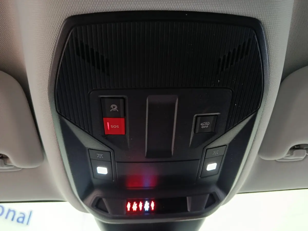 Vue en contre-plongée du panneau de commandes au plafond intérieur du Peugeot 308 gris foncé, avec bouton SOS rouge et éclairages blancs.
