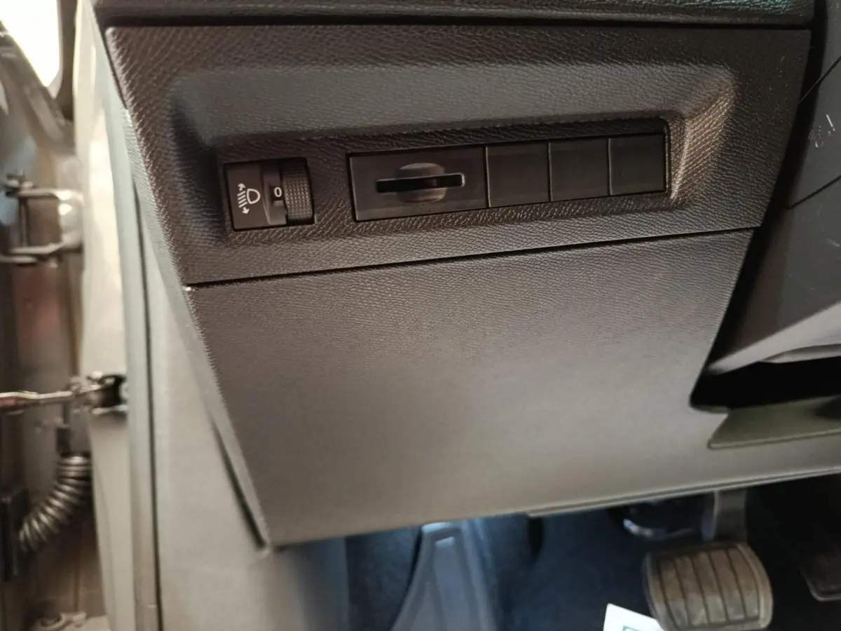 Vue rapprochée du panneau de réglage des phares et interrupteurs sur le côté gauche du tableau de bord gris foncé d’une Peugeot 308 2026.