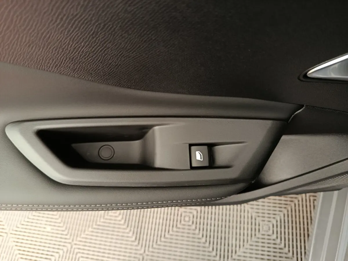 Détail de la commande de lève-vitre électrique sur la porte intérieure gris foncé d’une Peugeot 308 2026.