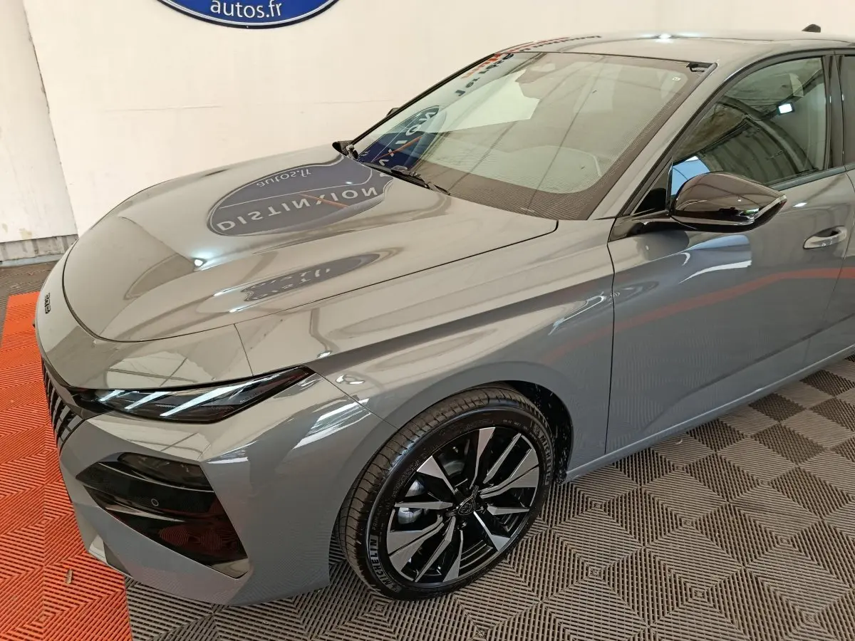 Vue 3/4 avant droit d'une Peugeot 308 gris foncé avec jantes alliage noires et phares LED ellipsoïdaux.