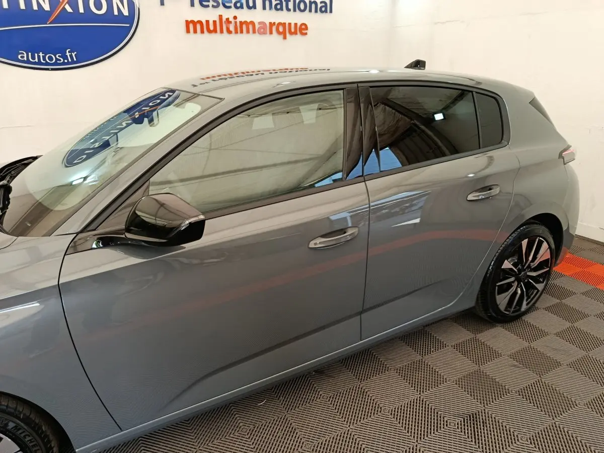 Vue latérale droite d'une Peugeot 308 gris foncé 2026 avec jantes alliage et rétroviseurs noirs.