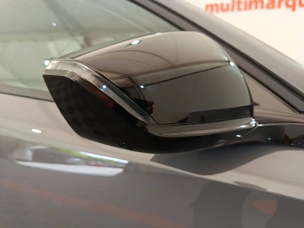 Rétroviseur droit noir brillant de la Peugeot 308 gris foncé, vue rapprochée en intérieur showroom.