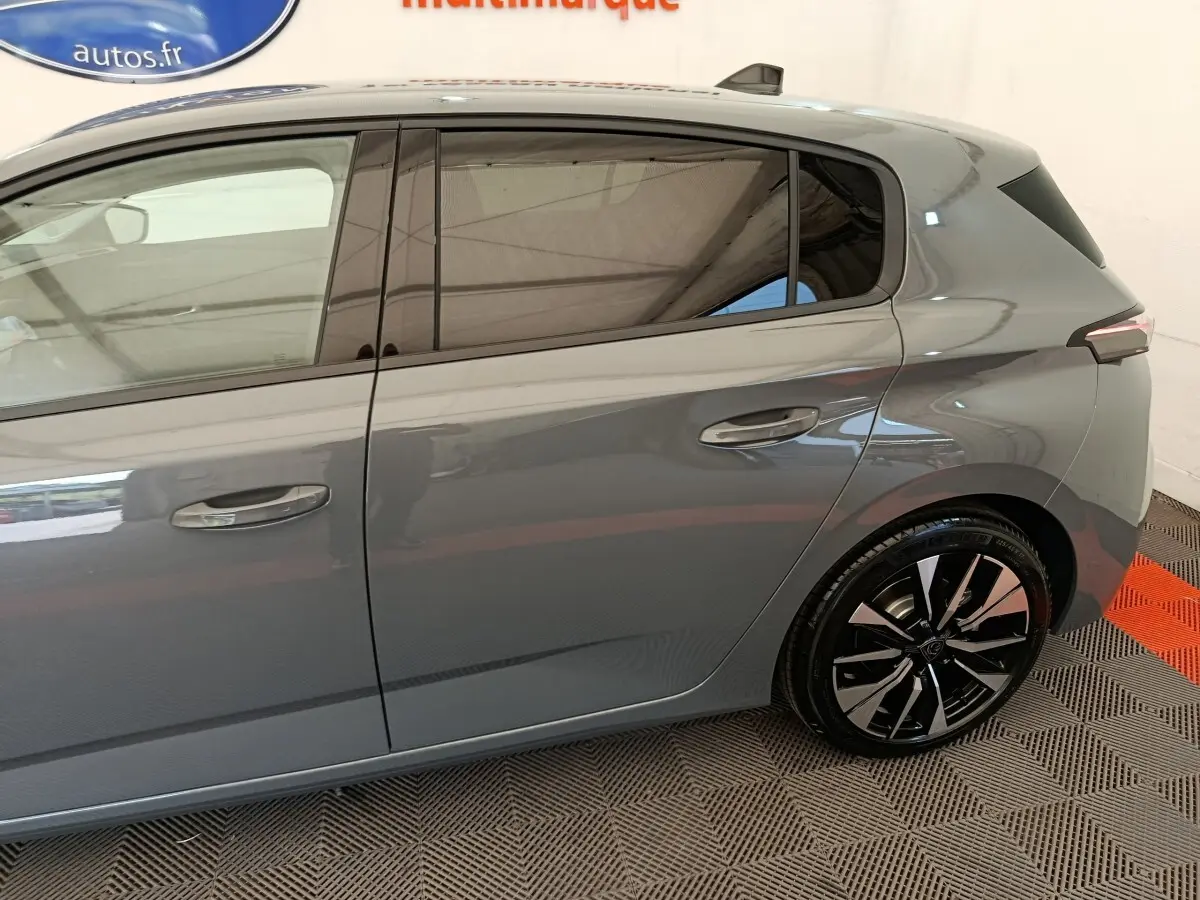 Vue latérale droite de la Peugeot 308 gris foncé avec jantes alliage noires et vitres teintées.