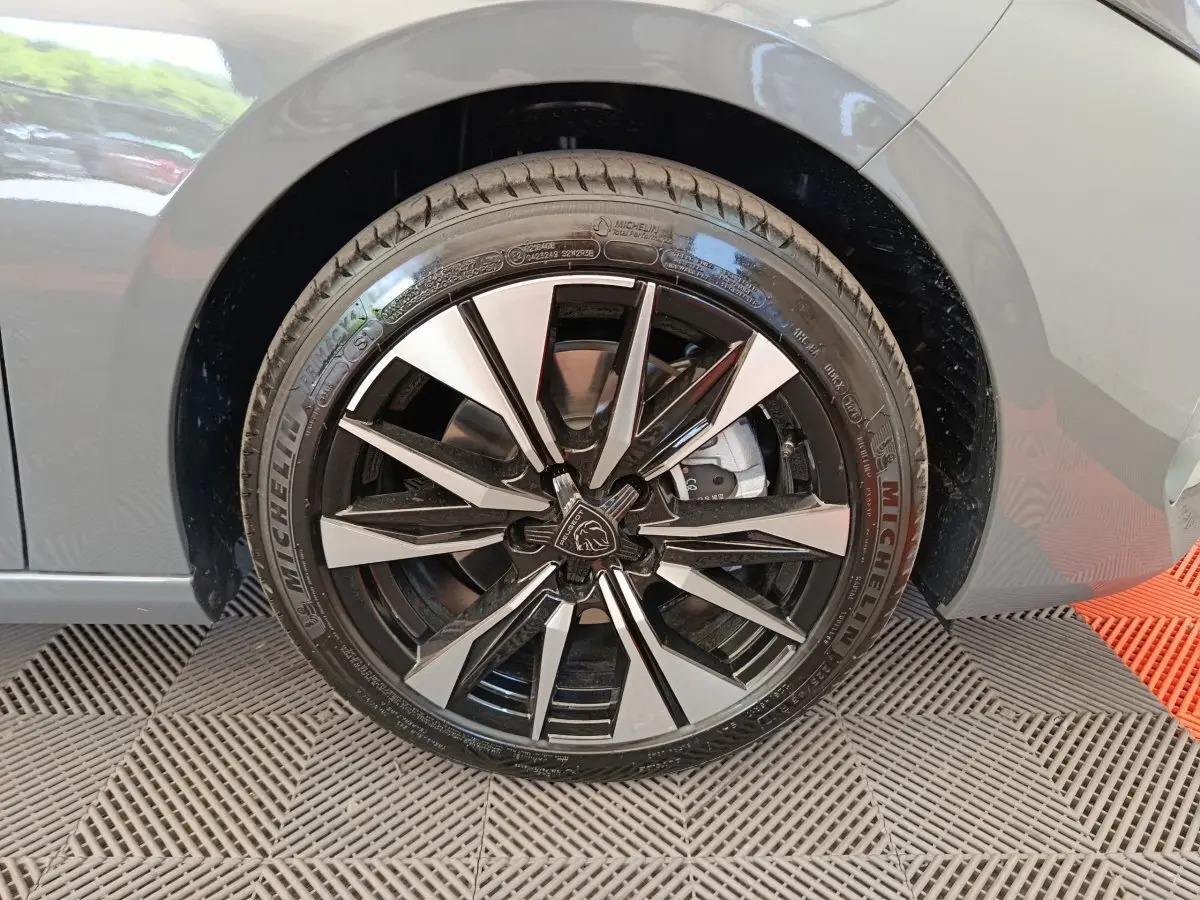 Gros plan sur la roue avant droite de la Peugeot 308 gris foncé, avec jante alliage noire et argentée au design moderne.