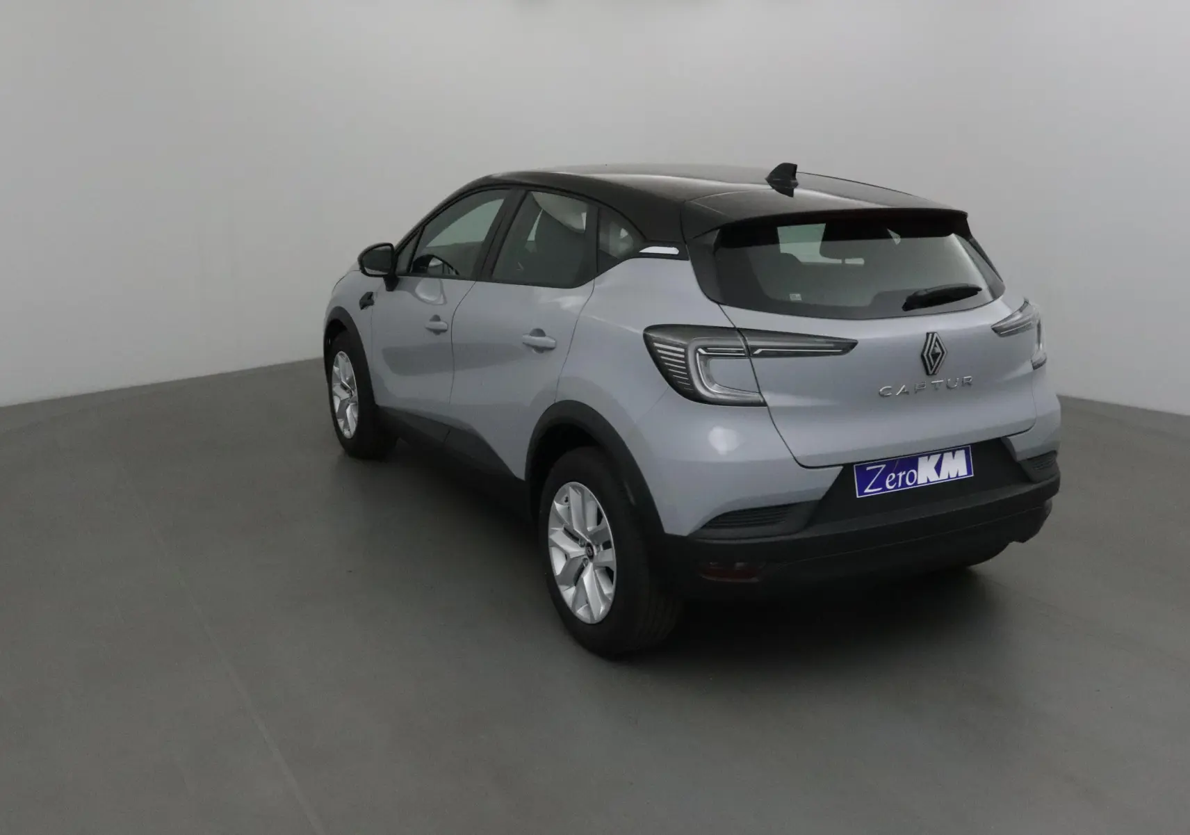 Renault Captur 2025 gris Rafale avec toit noir, vue 3/4 arrière droit, feux arrière LED et jantes alliage.