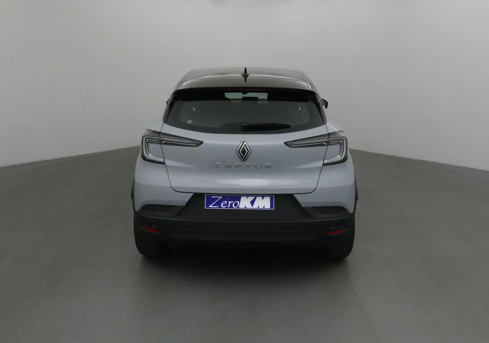 Vue arrière d'un Renault Captur gris Rafale avec toit noir, mettant en valeur ses feux LED et son design moderne.