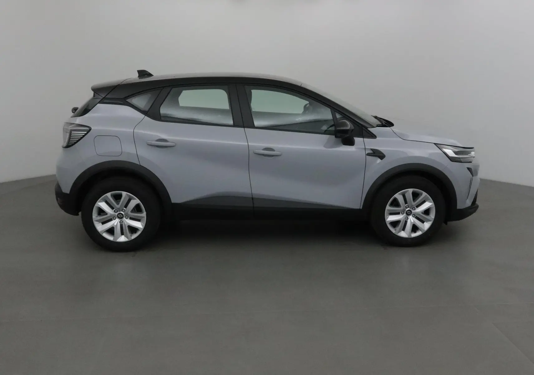 Profil droit du Renault Captur 1.0 TCE 90 Evolution 2025 en gris Rafale avec toit noir et jantes argentées.