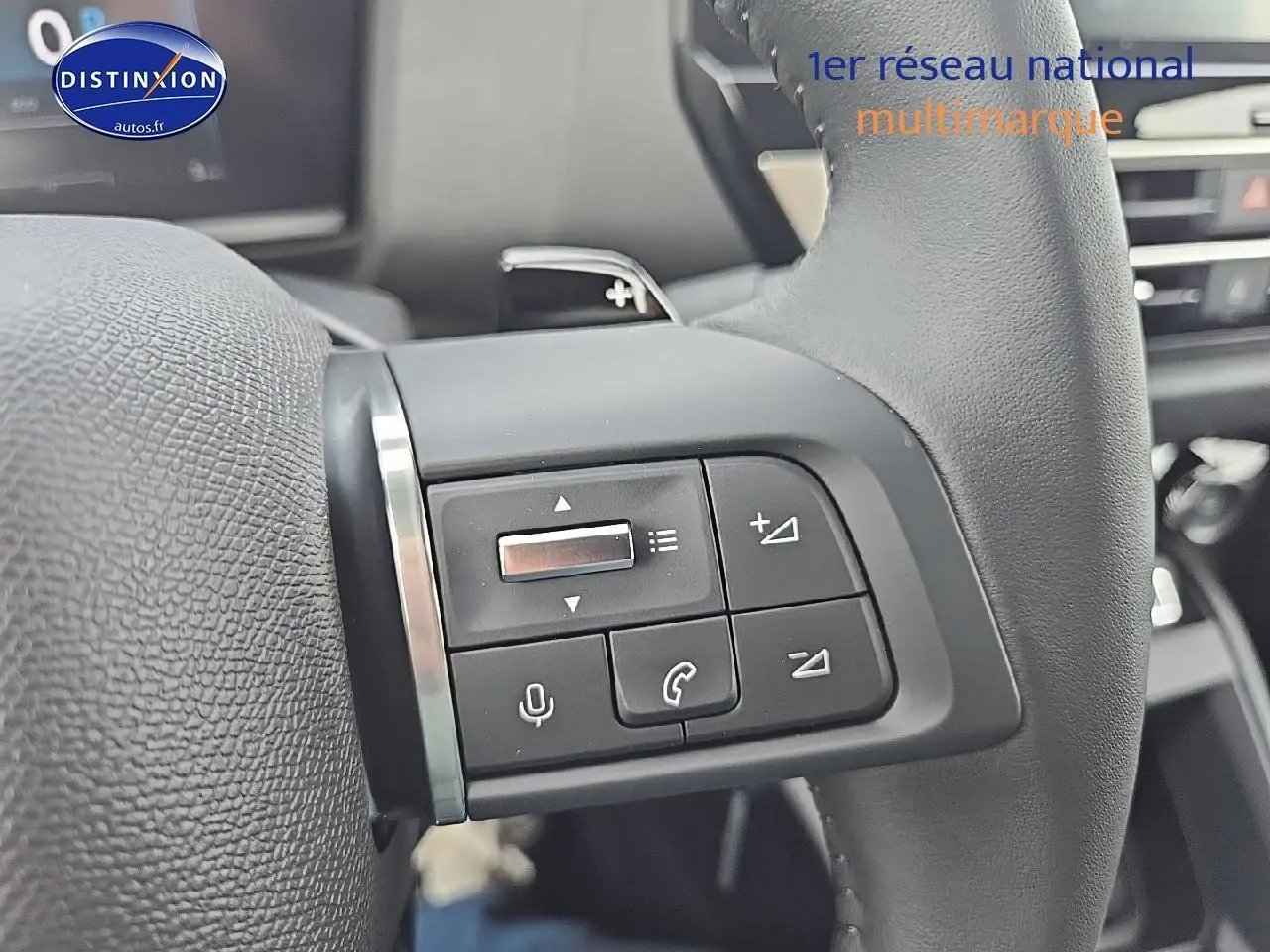 Gros plan sur les commandes audio au volant en cuir noir de la Citroën C4 hybride 2025, intérieur moderne.