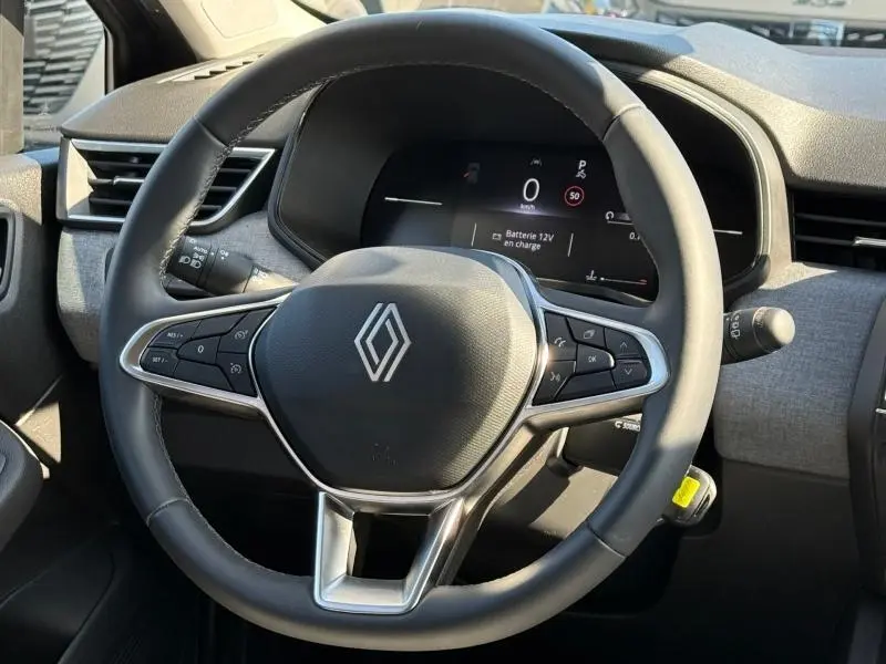 Vue rapprochée du volant cuir noir multifonction de la Renault Clio gris schiste avec tableau de bord numérique allumé.