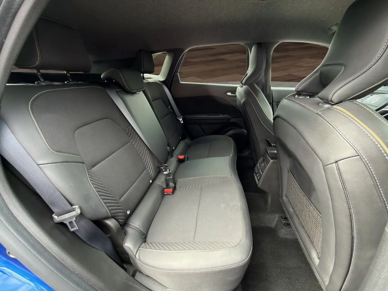 Vue intérieure côté droit montrant la banquette arrière en tissu noir avec surpiqûres contrastantes du Renault Symbioz Bleu Iron.