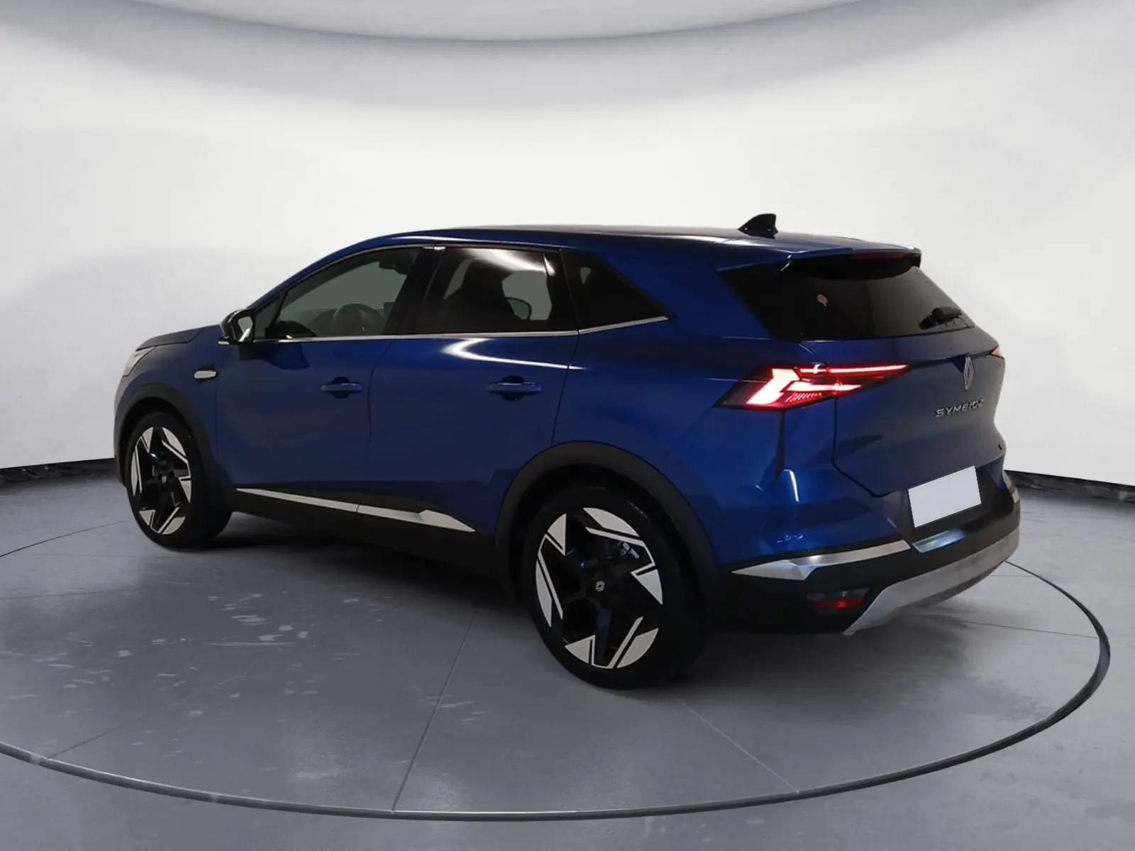 Renault Symbioz E-Tech Full Hybrid 145 Iconic bleu iron, vue 3/4 arrière droit avec feux arrière allumés.