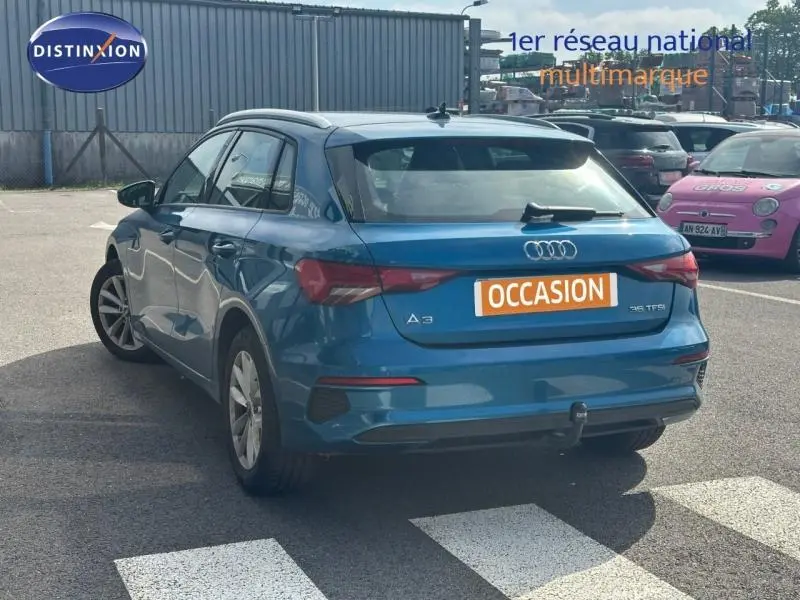 Vue 3/4 arrière droite d'une Audi A3 Sportback 35 TFSI bleu Atoll métallisé avec attelage de remorque visible.