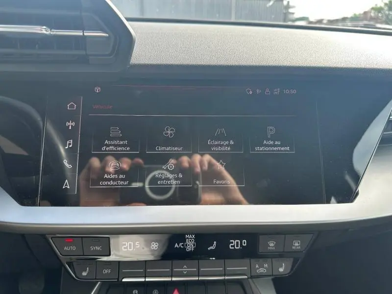 Vue rapprochée de l’écran tactile central et de la console de la Audi A3 Sportback 35 TFSI bleu Atoll, affichant les réglages du véhicule.