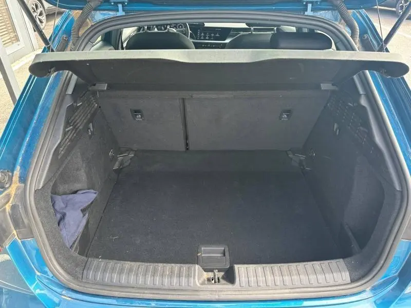 Coffre ouvert vu de l'arrière d'une Audi A3 Sportback 35 TFSI bleu Atoll métallisé, espace de chargement vide.