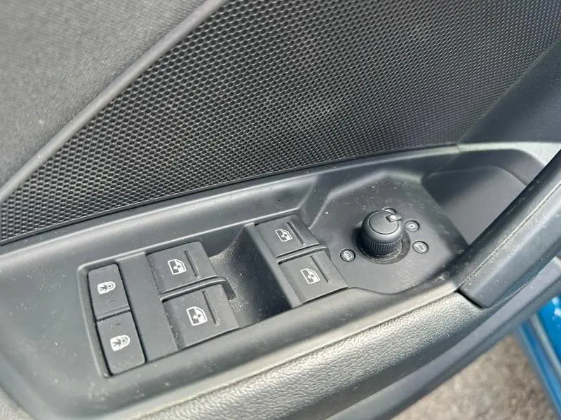 Gros plan sur les commandes des vitres et des rétroviseurs côté conducteur de l'Audi A3 Sportback bleu Atoll métallisé.
