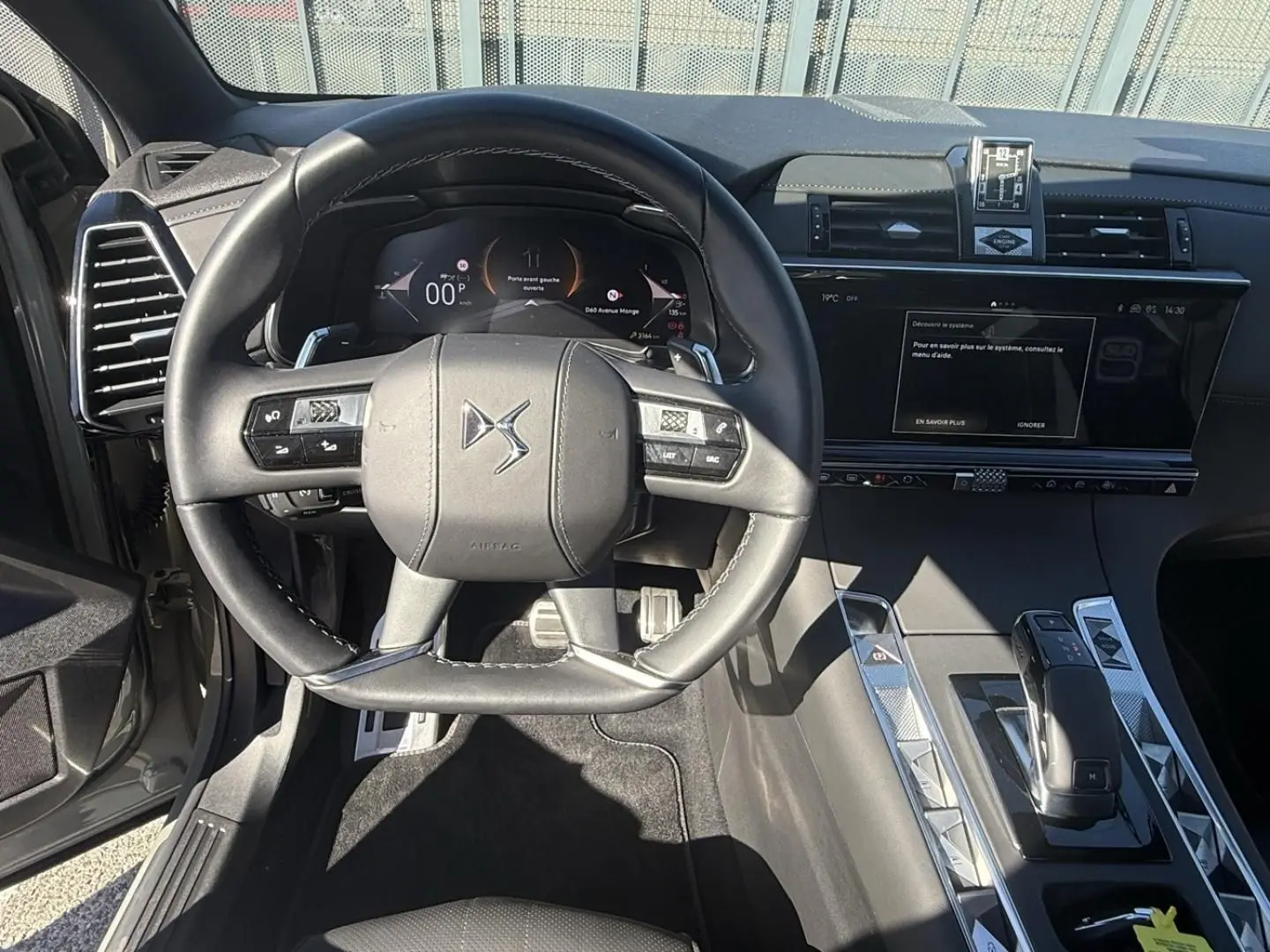 Vue intérieure centrée sur le volant et la console d'une DS7 1.5 HDI 130cv gris métal, avec tableau de bord digital et écran tactile.