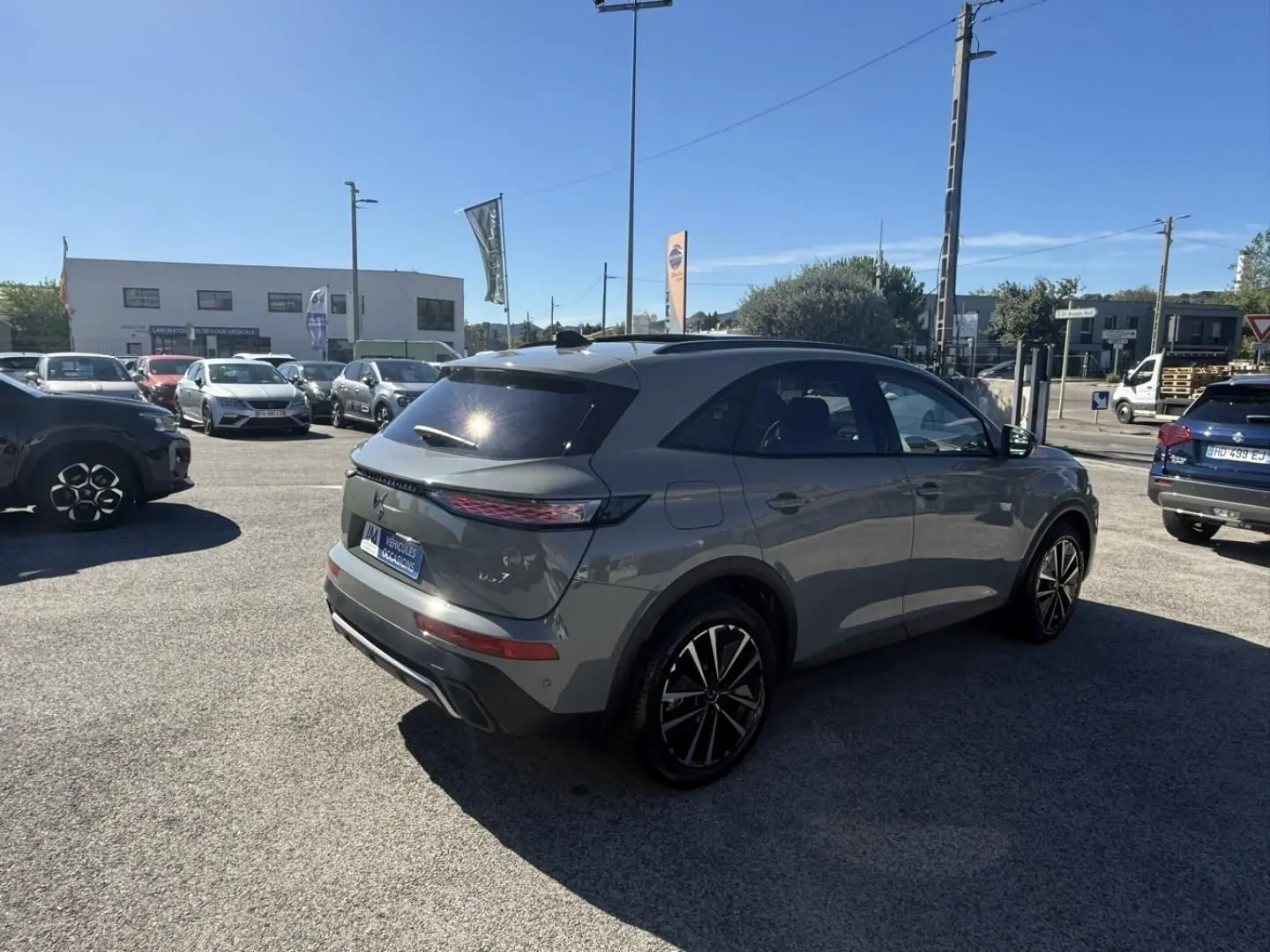 DS7 1.5 HDI 130cv Etoile gris métal vu en 3/4 arrière droit sur un parking en extérieur lumineux.