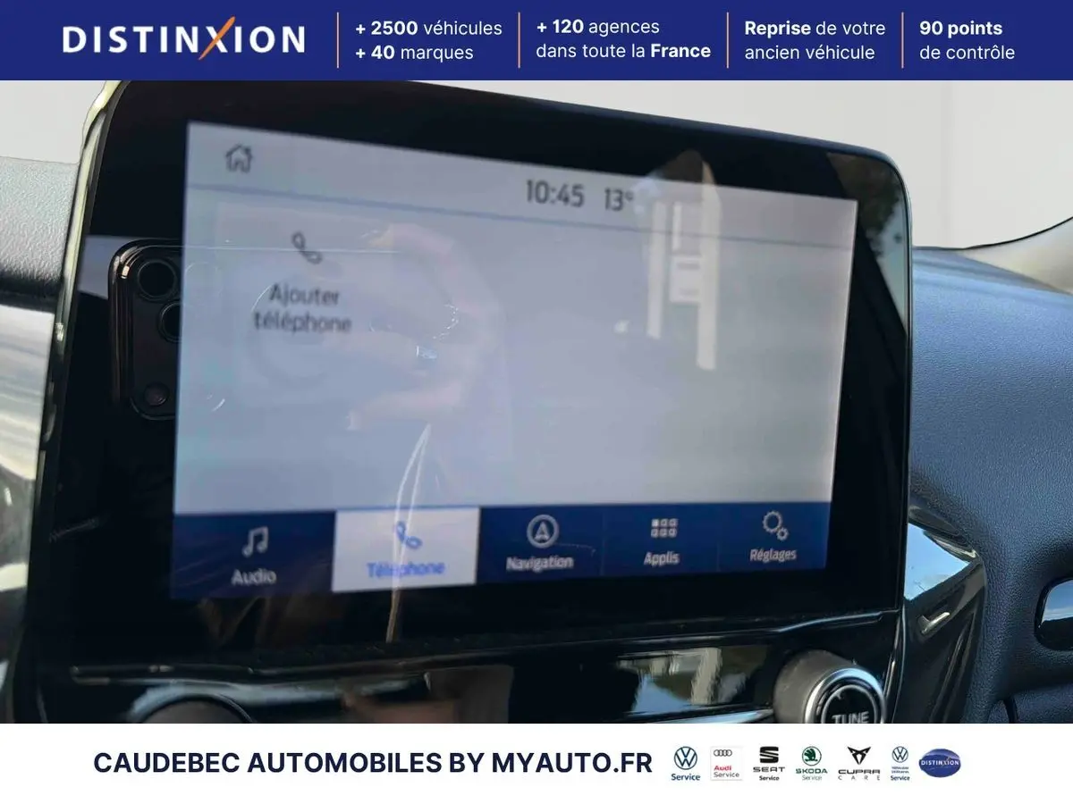 Vue intérieure centrée sur l'écran tactile du système SYNC4 du Ford Puma bleu 2024, avec commandes vocales visibles.