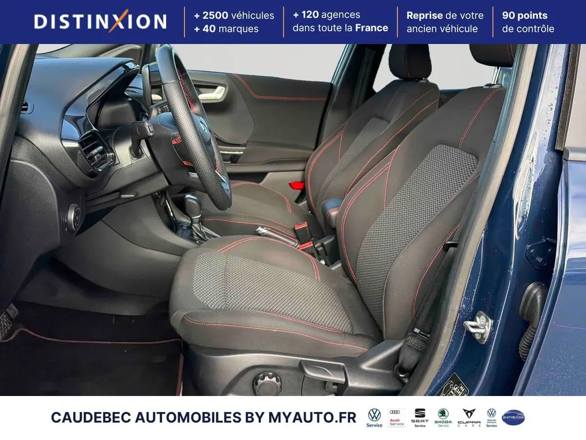 Vue intérieure côté conducteur du Ford Puma bleu 2024, sièges sport noirs avec surpiqûres rouges et volant cuir.