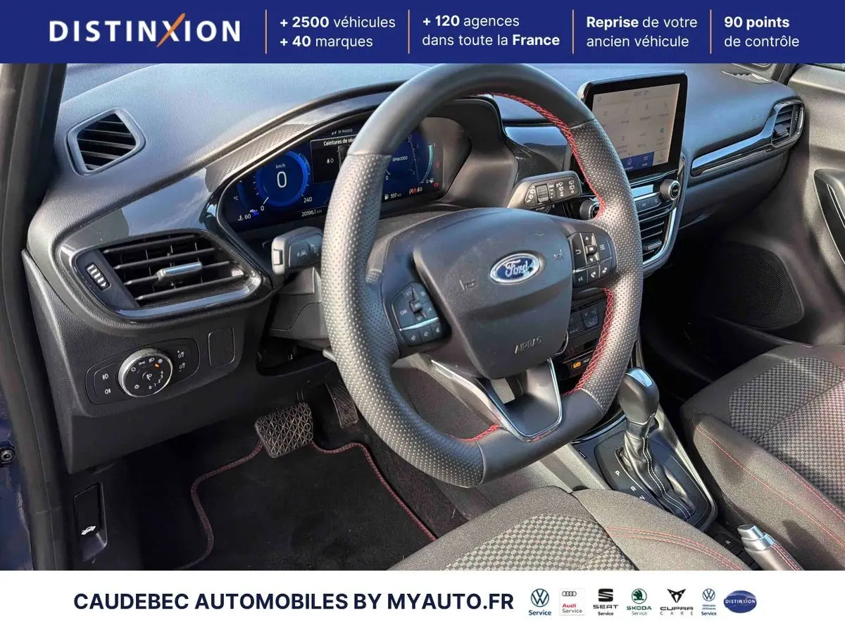 Vue intérieure côté conducteur du Ford Puma 2024, volant cuir perforé avec surpiqûres rouges et console centrale moderne.
