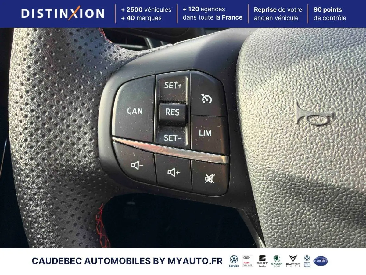 Gros plan sur les commandes de régulateur de vitesse au volant perforé avec surpiqûres rouges du Ford Puma bleu 2024.